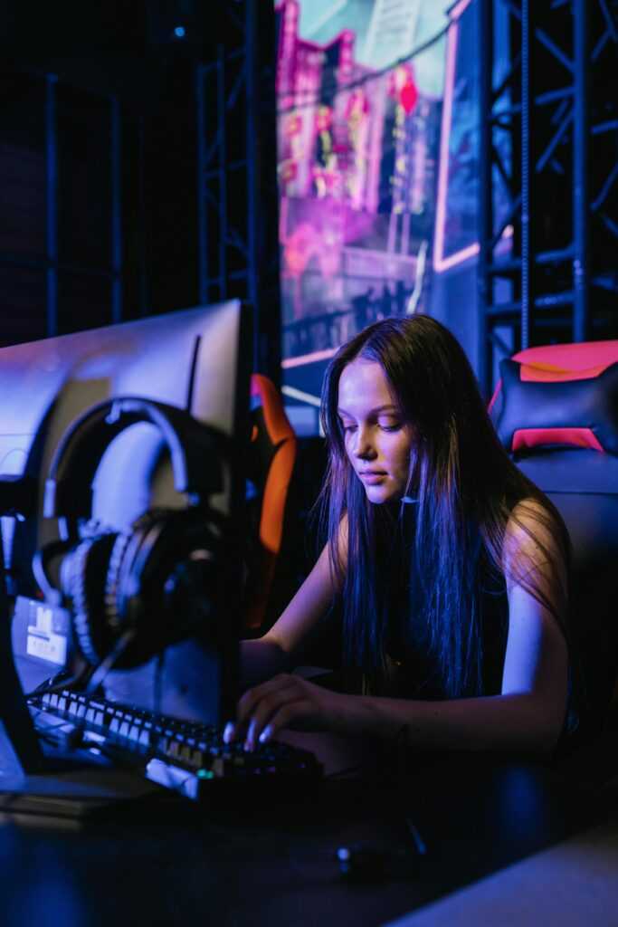 Woman immersed in gaming on a computer with headphones, highlighting esports culture.