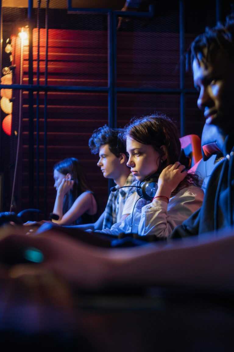 A group of young adults intensely focused on a gaming session, wearing headsets in an esports setting.