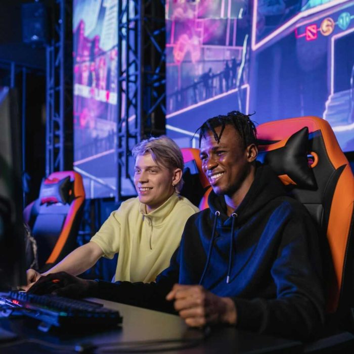 Two young men enjoying a competitive gaming session at an eSports event. Indoors with neon lights.